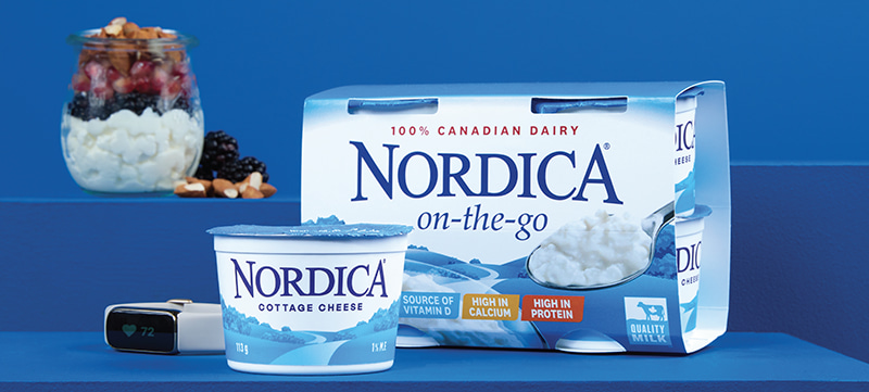 Nordica On-the-Go Plain 1% on a table with a smart watch and a parfait in the light blue background.